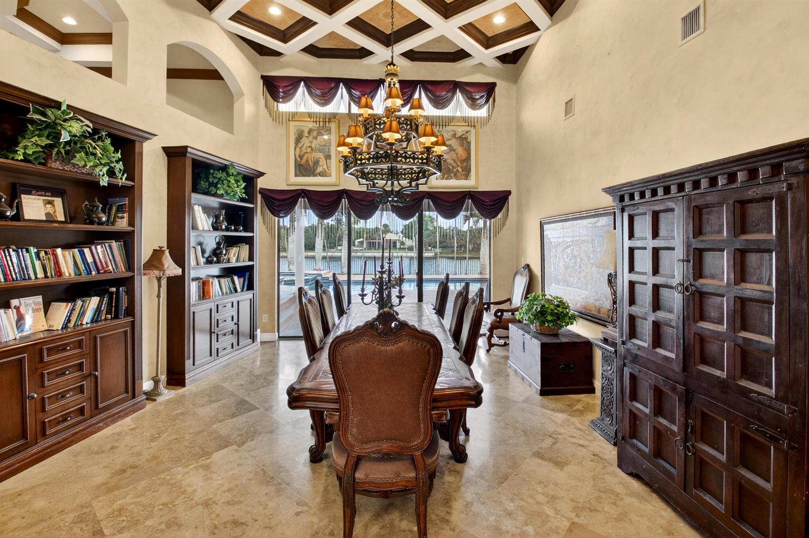 A formal dining room features a coffered ceiling, stone floors, and a view of water — 1940 SW 7th Place, Boca Raton FL 33486, BOCA RATON, FL