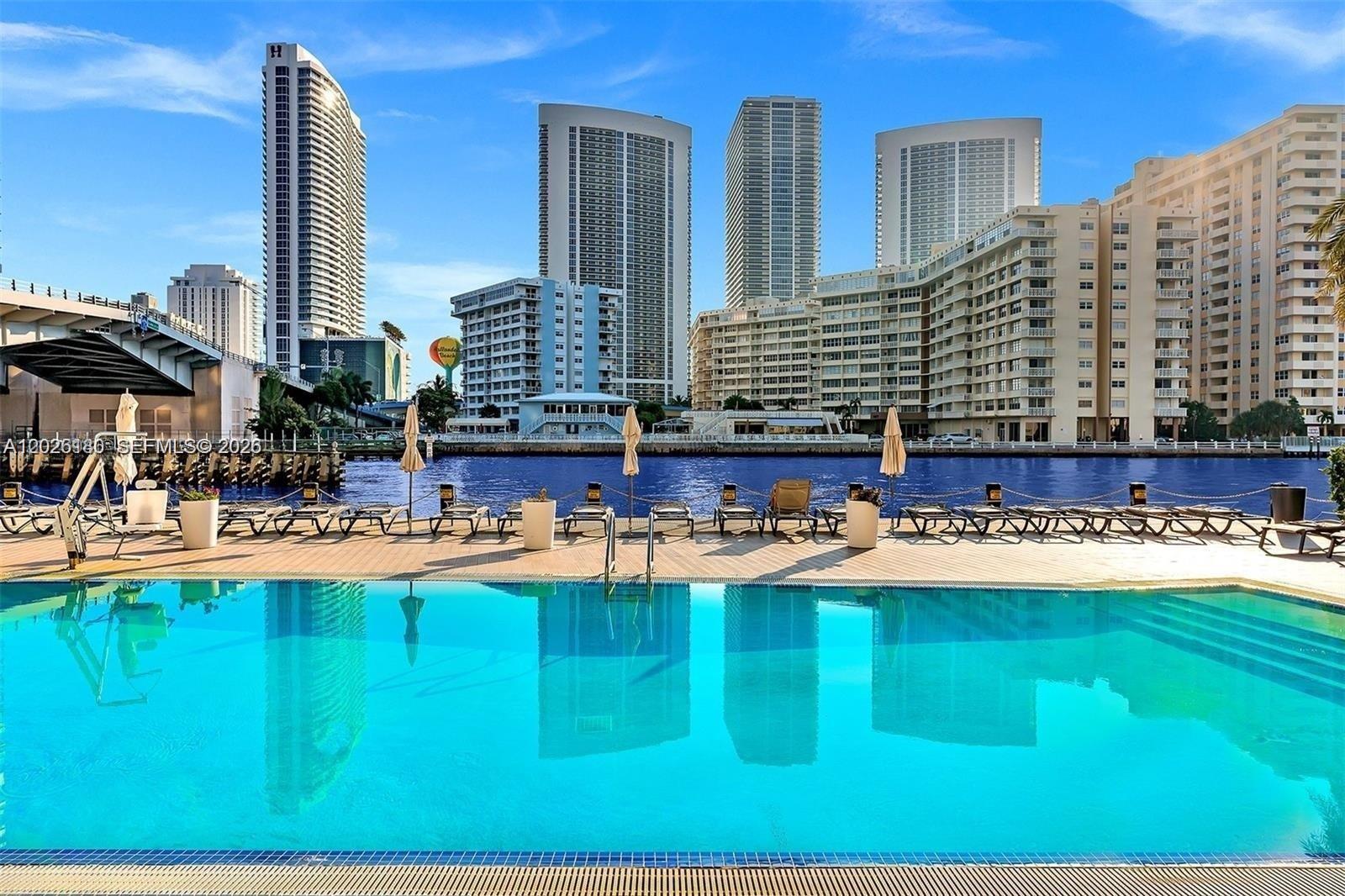 A swimming pool overlooks a canal with high-rise buildings in the background — 2602 E E HALLADALE # T3105, Hallandale Beach FL 33009, HALLANDALE BEACH, FL