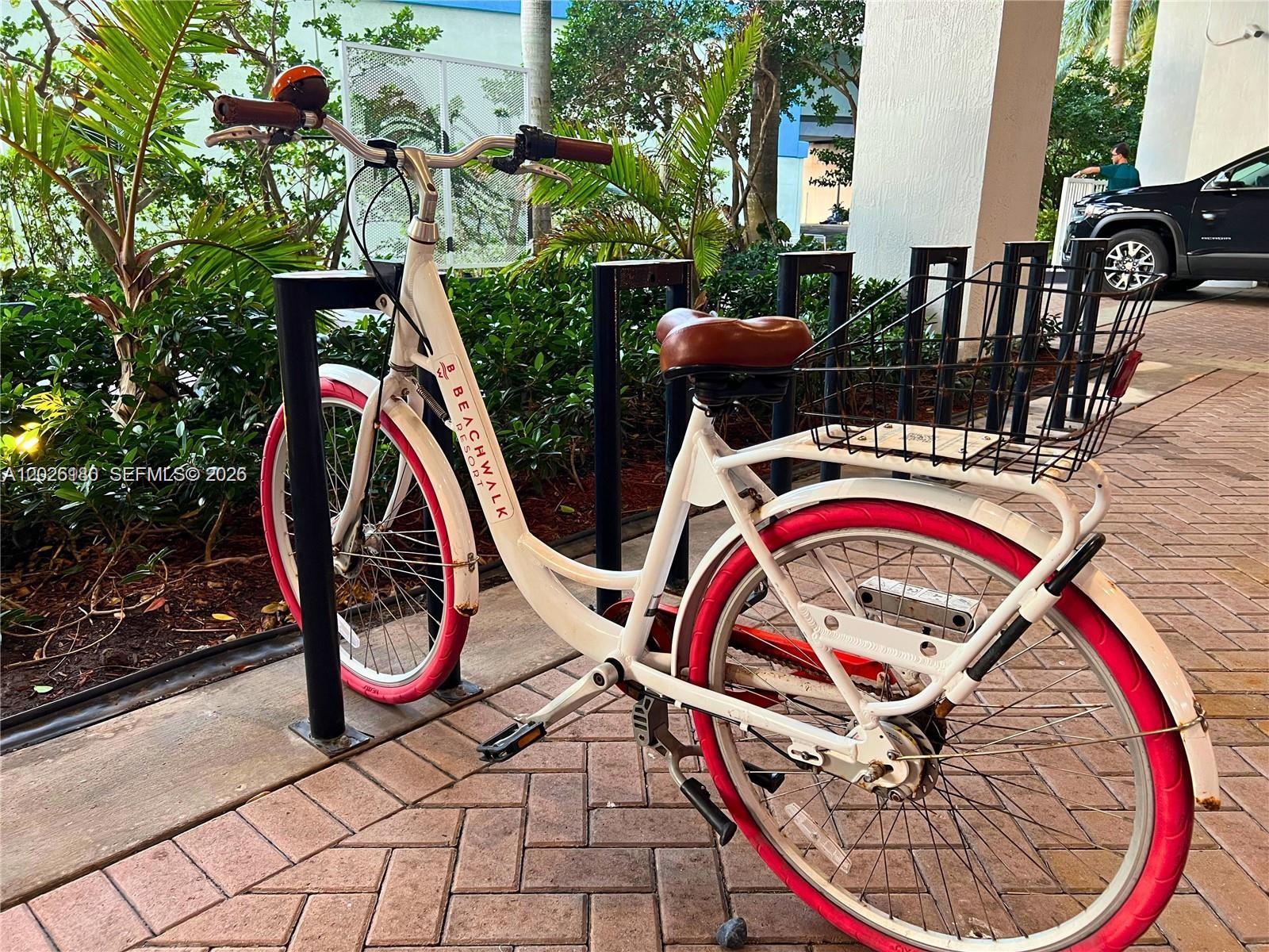 A white cruiser bicycle with pink tires and a rear basket is parked outdoors — 2602 E E HALLADALE # T3105, Hallandale Beach FL 33009, HALLANDALE BEACH, FL