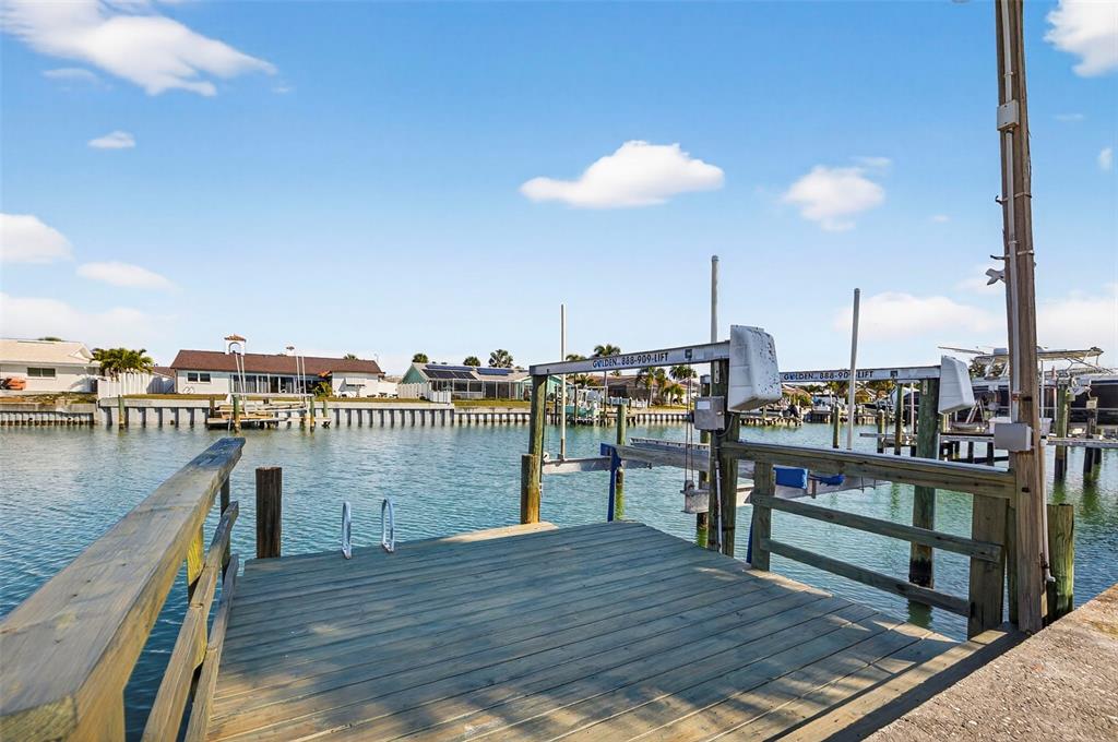 A wooden boat dock with a mechanical boat lift extends over a canal — 4426 43RD STREET S, ST PETERSBURG, FL