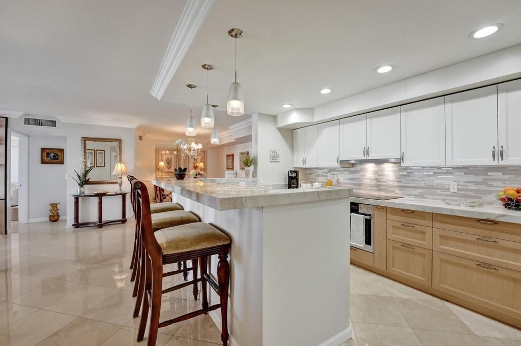 A swimming pool is surrounded by palm trees, stone planters, and multi-story residential buildings — 3606 S Ocean Boulevard # 603, Highland Beach FL 33487, HIGHLAND BEACH, FL