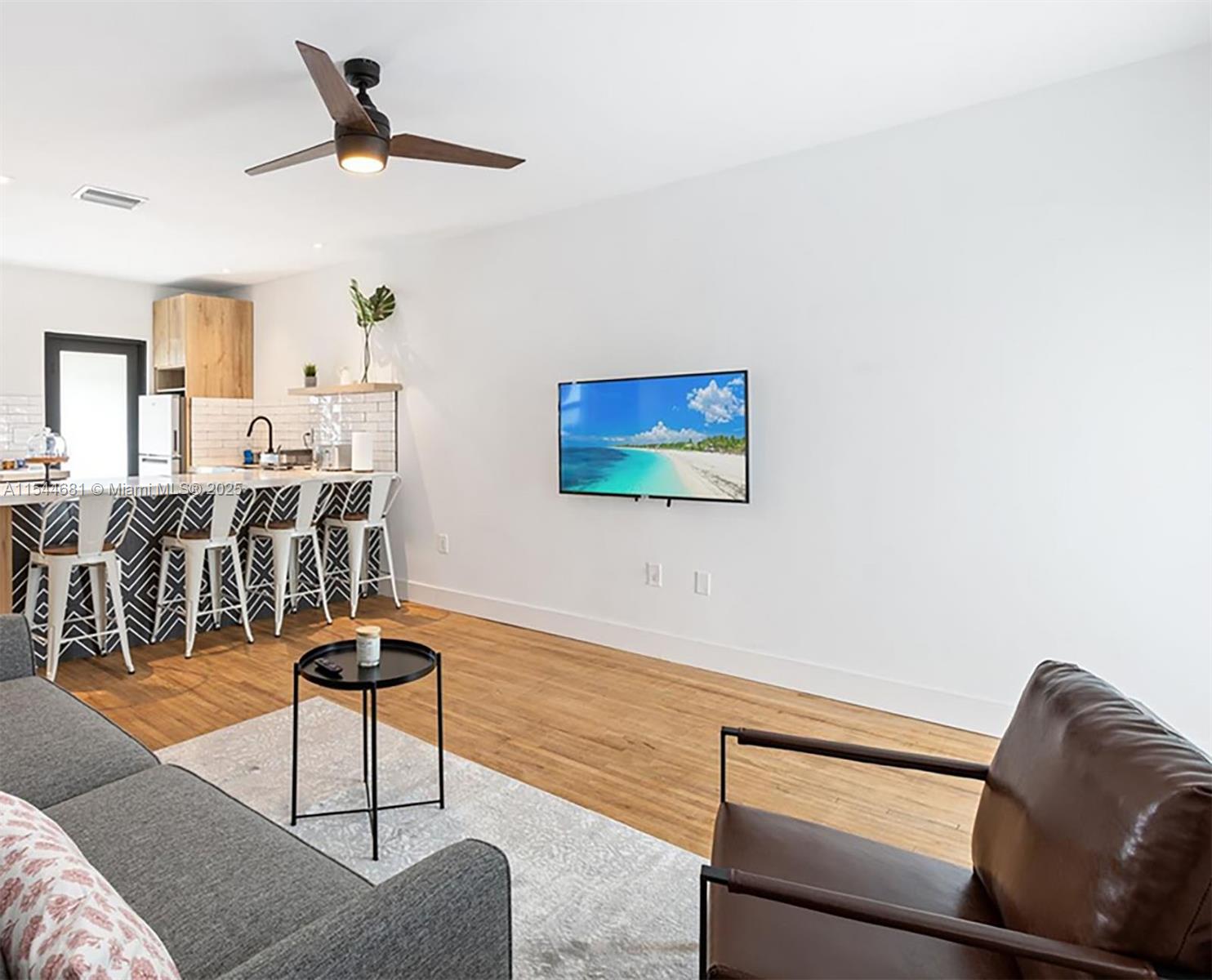 A living room features a wall-mounted television, a ceiling fan, and an adjacent kitchen island — 740 SW 9th St # 1, Miami FL 33130, MIAMI, FL