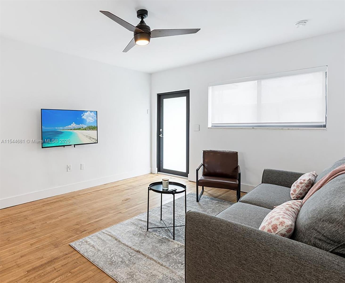 A living room features a gray sofa, a brown leather chair, and a wall-mounted television — 740 SW 9th St # 1, Miami FL 33130, MIAMI, FL