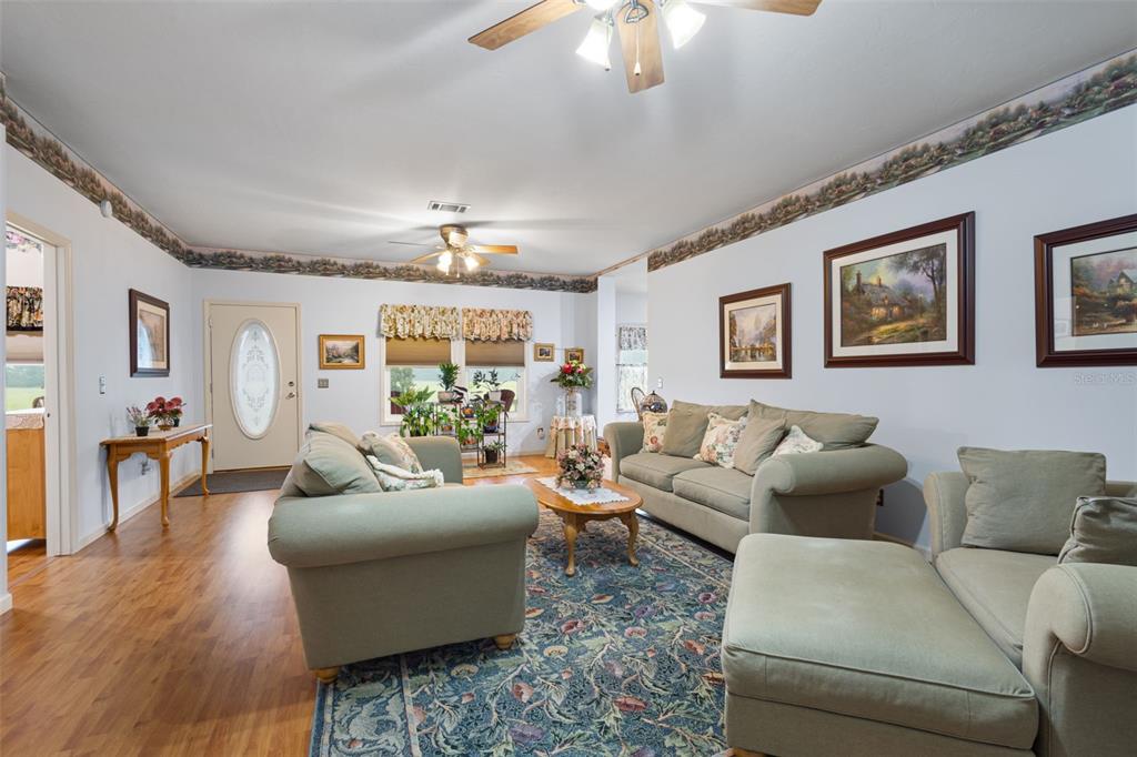 A living room features light blue walls, a patterned wallpaper border, and a blue rug — 4700 NW 26TH STREET, BELL, FL