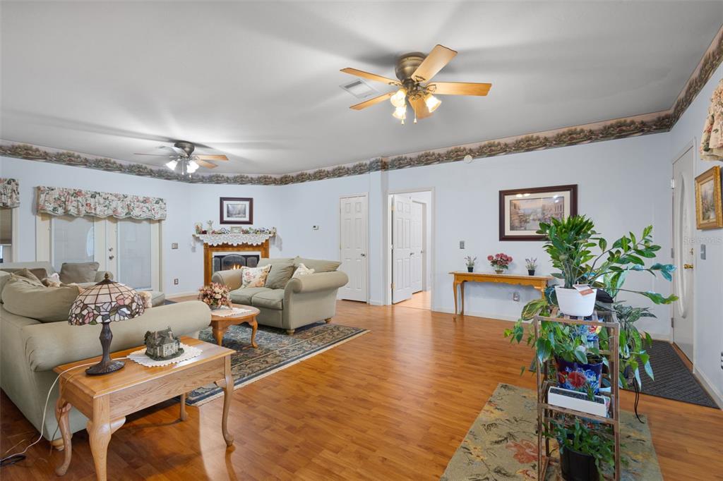 A living room features light blue walls, wood flooring, a fireplace, and two ceiling fans — 4700 NW 26TH STREET, BELL, FL