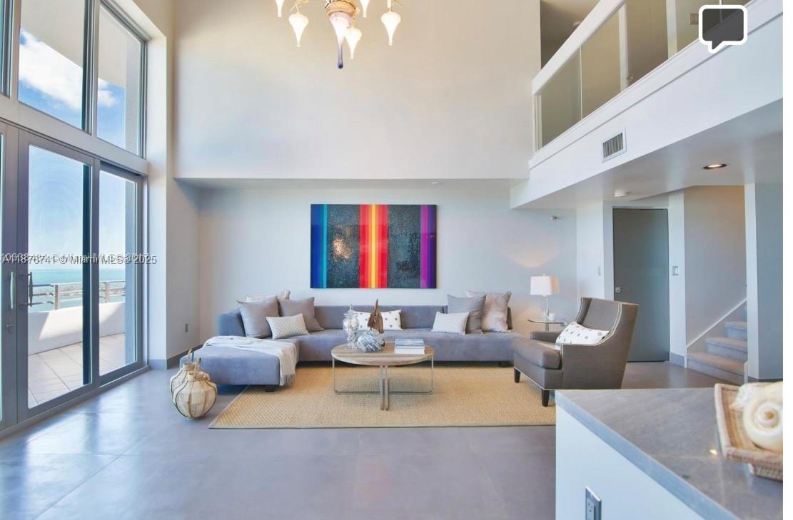 A modern living room features a sectional sofa, high ceilings, large windows, and colorful artwork — 151 SE 15th Rd # 2703, Miami FL 33129, MIAMI, FL