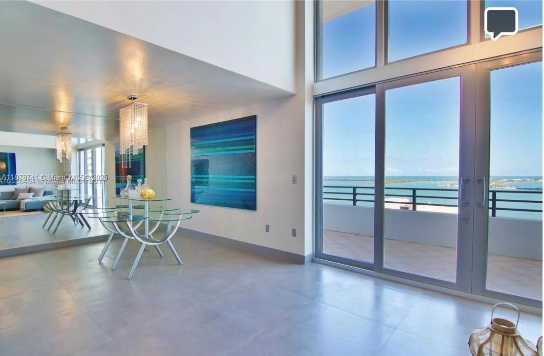 A dining area with a glass table, chandelier, and floor-to-ceiling windows overlooking the ocean — 151 SE 15th Rd # 2703, Miami FL 33129, MIAMI, FL
