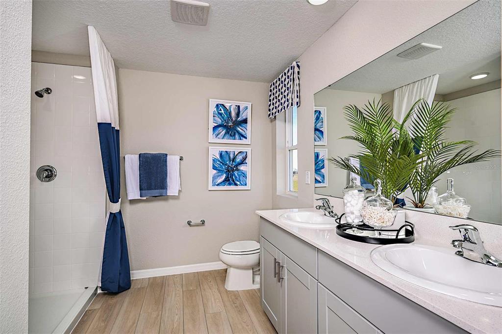 A bathroom features a double vanity, a walk-in shower, and blue-and-white floral wall art — 1723 VANILLA STREET, LAKE HAMILTON, FL