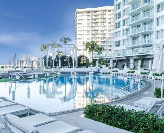 A large swimming pool sits on a terrace surrounded by lounge chairs and modern buildings — 1100 West Ave # 409, Miami Beach FL 33139, MIAMI BEACH, FL