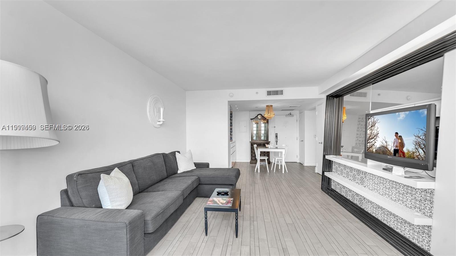 A living room features a grey sectional sofa, a coffee table, and a wall-mounted television — 1100 West Ave # 409, Miami Beach FL 33139, MIAMI BEACH, FL