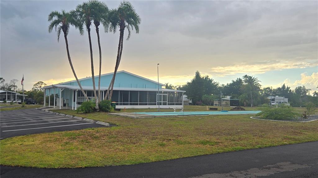 A light blue community building with a screened porch stands next to a parking lot — 6767 SAN CASA DRIVE UNIT 84, ENGLEWOOD, FL