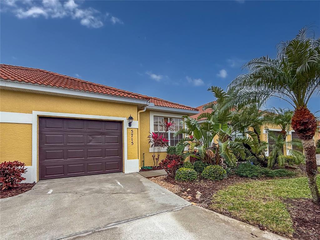 A yellow house with a brown garage door and a palm tree in the front yard — 5715 SPANISH POINT COURT, PALMETTO, FL
