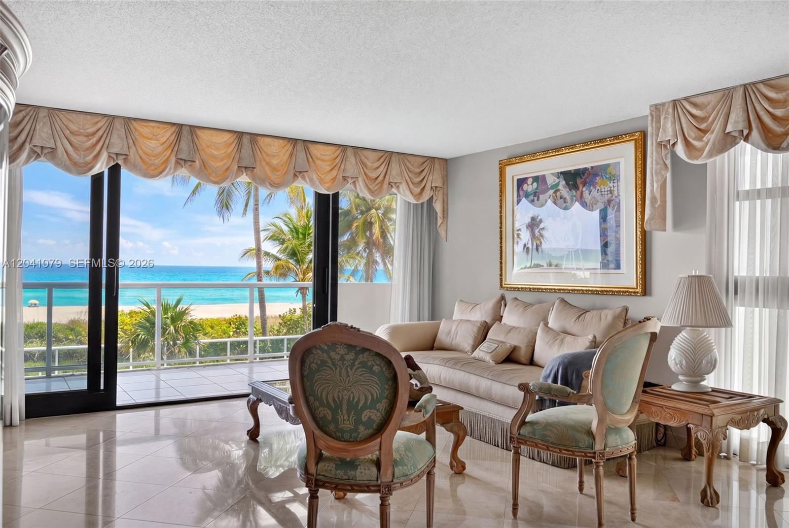 A living room with beige furniture, patterned chairs, and a balcony overlooking the ocean — 5757 Collins Ave # 405, Miami Beach FL 33140, MIAMI BEACH, FL
