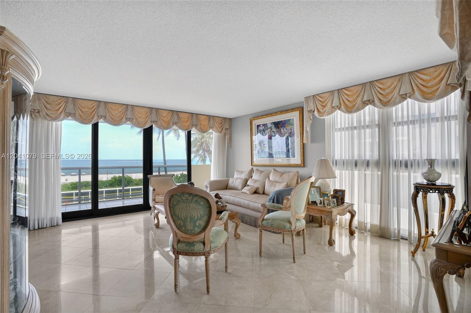 A living room with marble floors, traditional furniture, and a balcony overlooking the ocean — 5757 Collins Ave # 405, Miami Beach FL 33140, MIAMI BEACH, FL