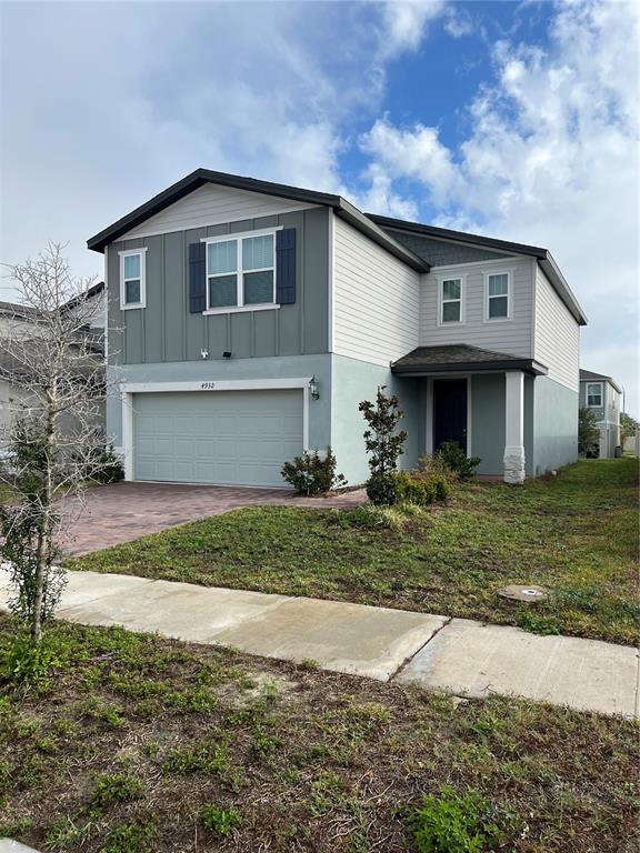 A two-story house with a light-colored garage, gray siding, and a paved driveway — 4932 MAINSAIL STREET, HAINES CITY, FL