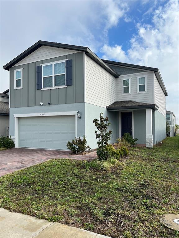 A two-story house features a light blue stucco base, gray siding, and a two-car garage — 4932 MAINSAIL STREET, HAINES CITY, FL