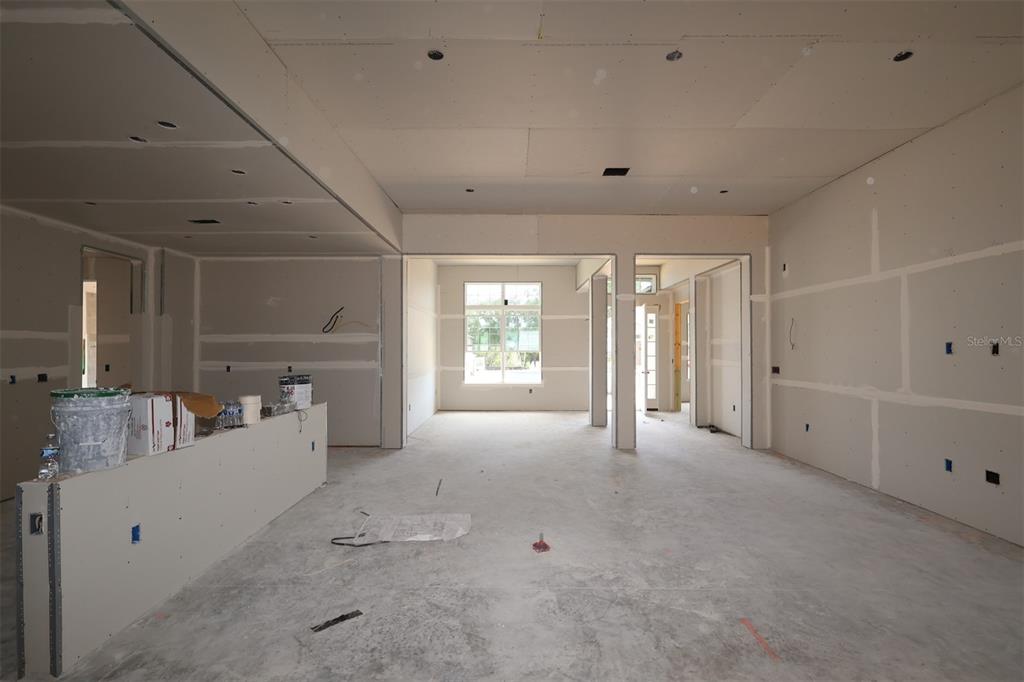 A kitchen under construction features white cabinets, a large island with blue protective film, and light wood flooring — 3223 ROSEVILLE DRIVE, APOPKA, FL