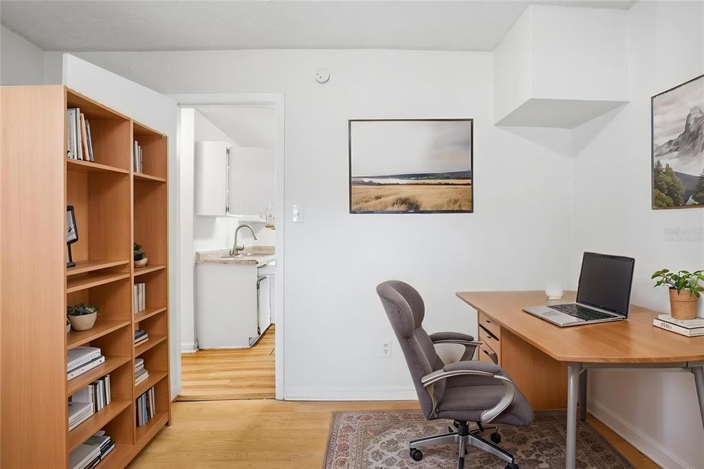A home office features a wooden desk, a bookshelf, and a doorway leading to a kitchen — 1510 E NAVAJO AVENUE, TAMPA, FL
