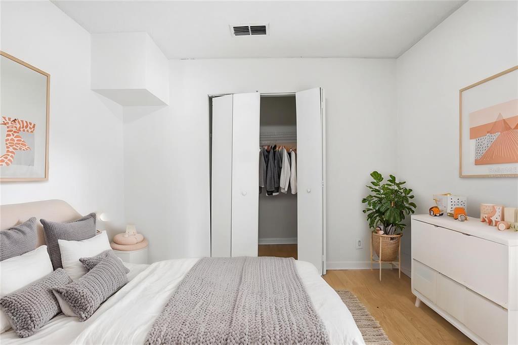 A bedroom features a bed with grey bedding, a white dresser, and an open closet — 1510 E NAVAJO AVENUE, TAMPA, FL