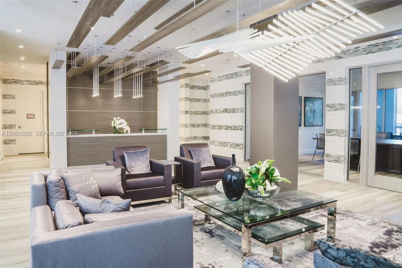 A modern lobby features a reception desk, lounge seating, and a large sculptural ceiling light — 1170 NW 11th St # 209, Miami FL 33136, MIAMI, FL