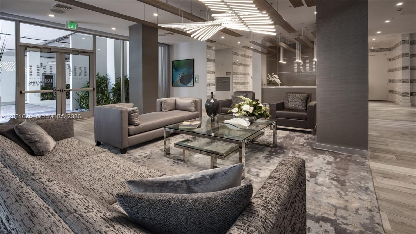 A modern lobby features gray sofas, a glass coffee table, and a unique geometric chandelier — 1170 NW 11th St # 209, Miami FL 33136, MIAMI, FL