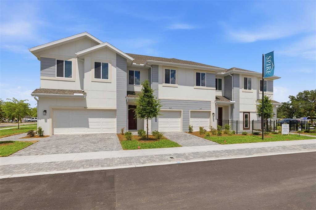 A multi-unit residential building with light-colored siding, paved driveways, and attached garages — 5819 ANGELA LEYLA PLACE, RIVERVIEW, FL