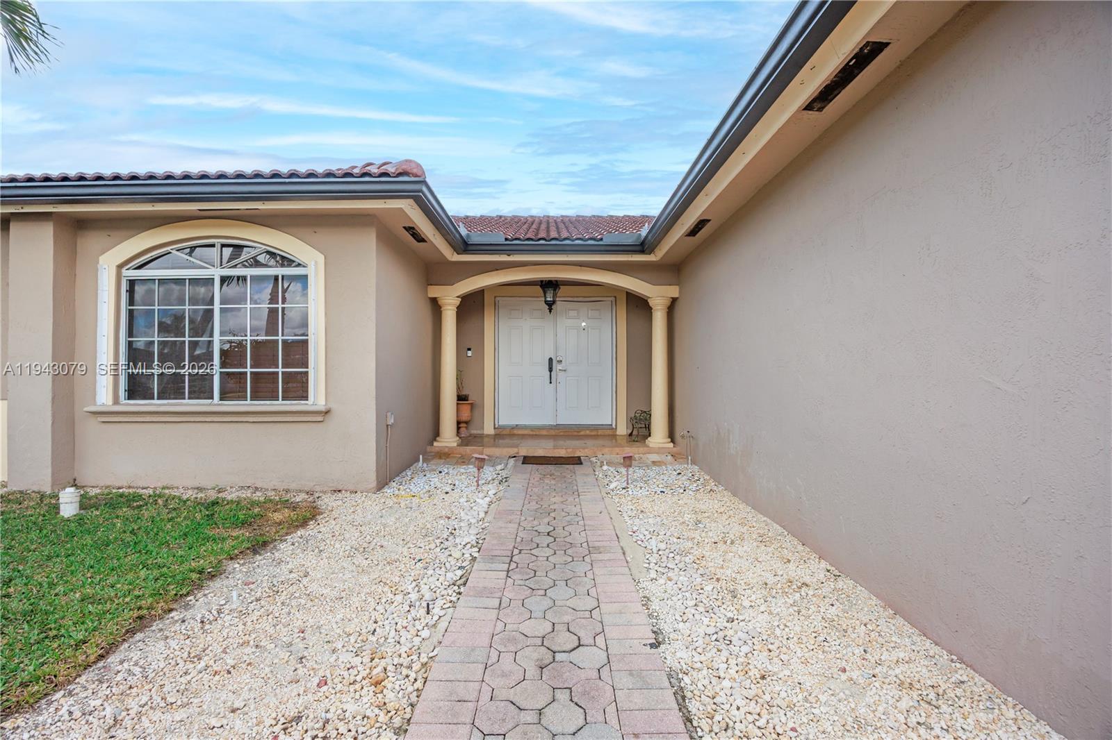 A paved walkway leads to the double front doors of a tan stucco house — 15330 SW 170th Ter, Miami FL 33187, MIAMI, FL