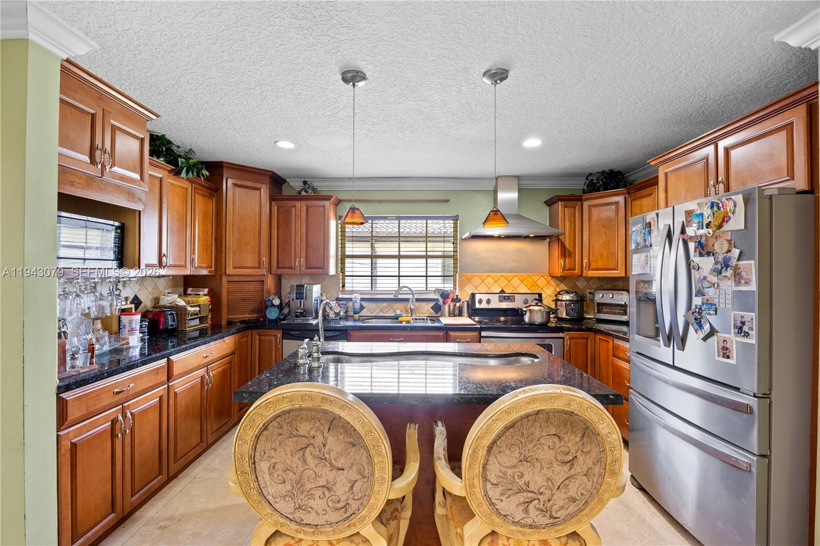 A kitchen features wooden cabinets, granite countertops, a central island, and stainless steel appliances — 15330 SW 170th Ter, Miami FL 33187, MIAMI, FL