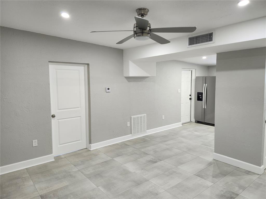 A room with gray walls, tile flooring, a ceiling fan, and a stainless steel refrigerator — 5212 OLD CHENEY HIGHWAY, ORLANDO, FL