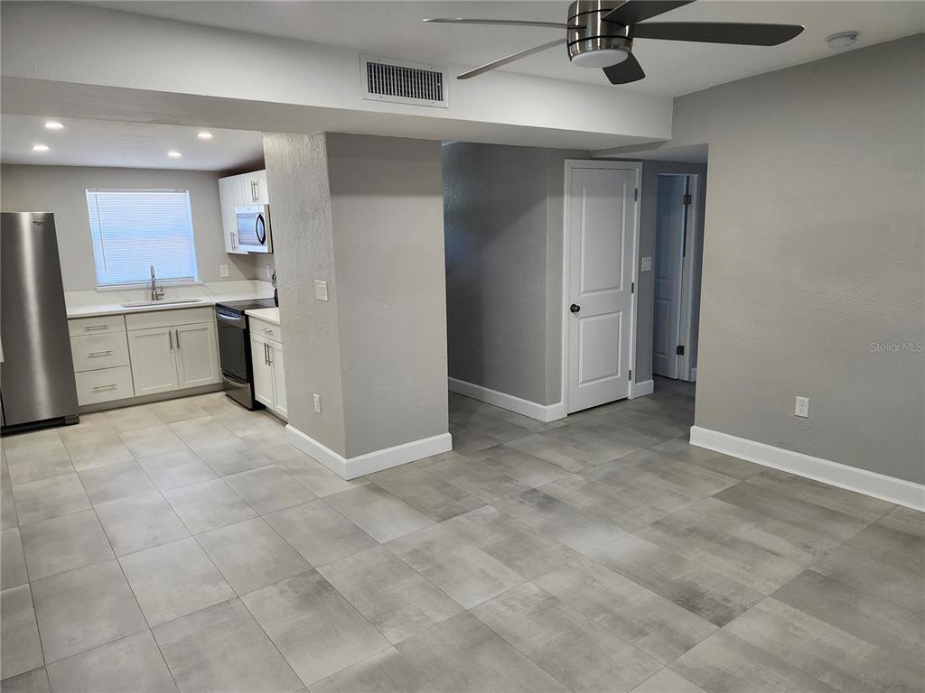 A kitchen with white cabinets and stainless steel appliances opens into a gray-walled living area — 5212 OLD CHENEY HIGHWAY, ORLANDO, FL