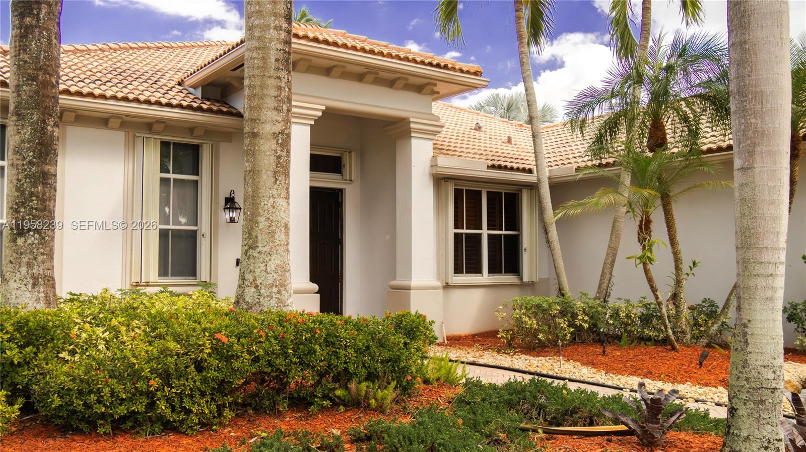 The exterior of a single-story home features a tiled roof, white walls, and palm trees — 2288 Quail Roost Dr # 0, Weston FL 33327, WESTON, FL
