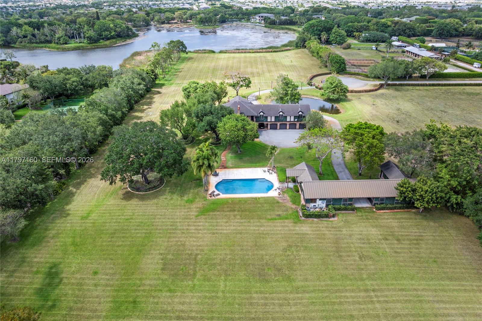 An aerial view shows a house with a pool, large lawn, and a nearby lake — 8700 Surrey Ln, Boca Raton FL 33496, BOCA RATON, FL