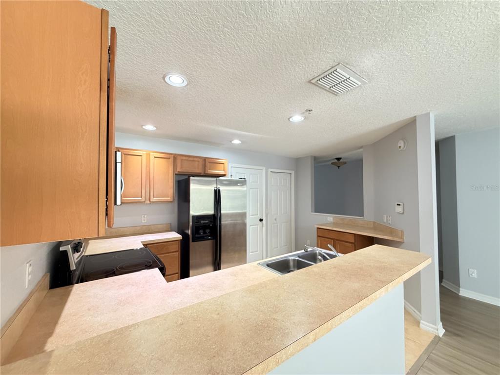 A kitchen features light wood cabinets, laminate countertops, stainless steel appliances, and a breakfast bar — 290 GLOWING PEACE LANE UNIT 52, ORLANDO, FL