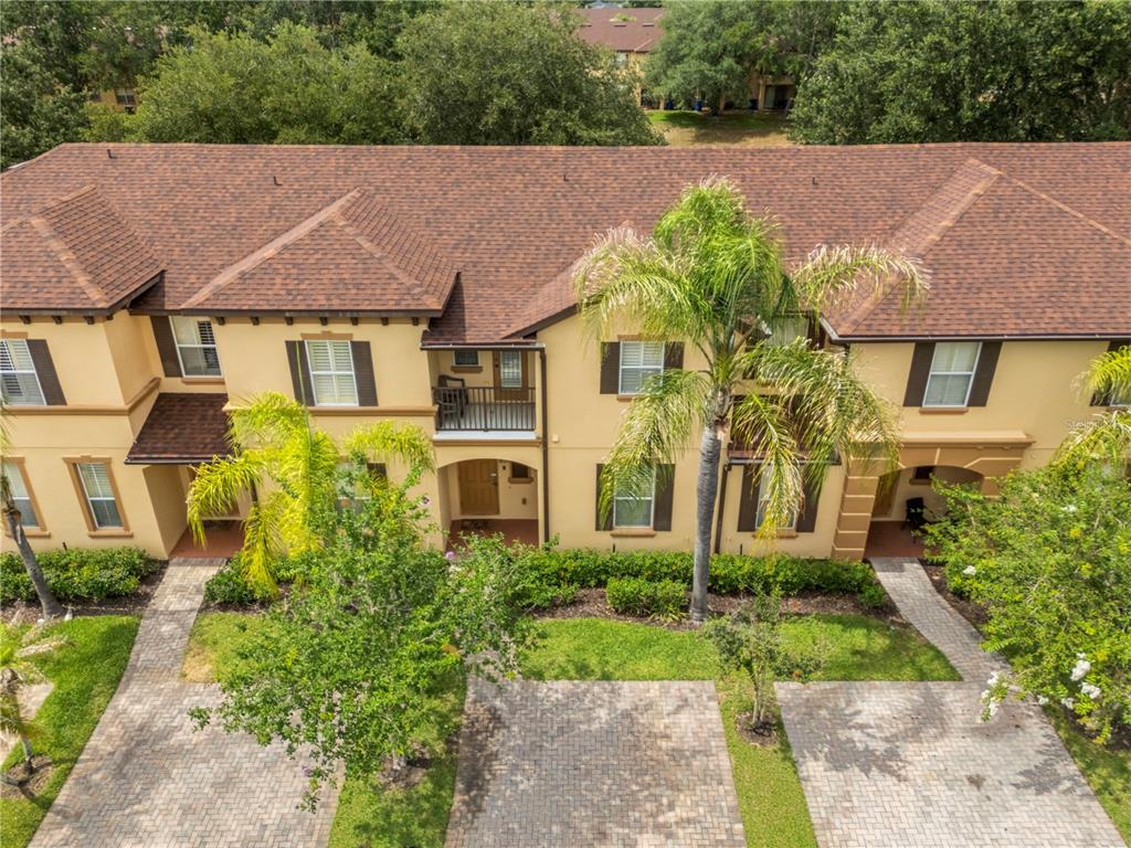 An aerial view of a two-story townhouse complex with a brown shingled roof and landscaping — 3725 CALABRIA AVENUE, DAVENPORT, FL