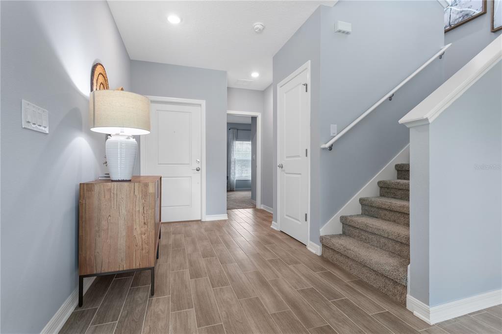 An entryway features light gray walls, wood-look tile flooring, a staircase, and a wooden console — 1185 SAND TRAP COURT, DAYTONA BEACH, FL