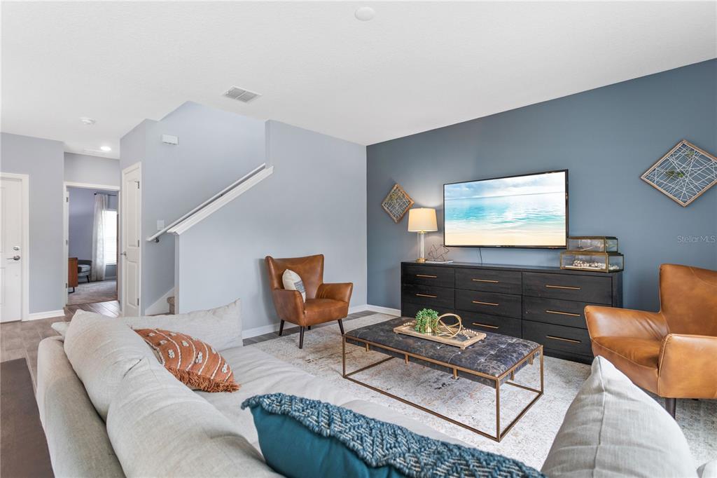 A living room features a blue accent wall, a television, and two leather armchairs — 1185 SAND TRAP COURT, DAYTONA BEACH, FL