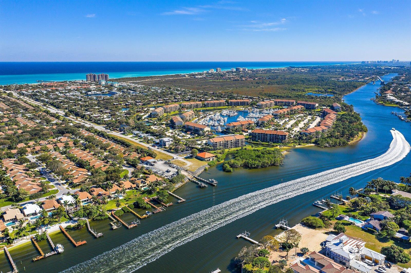 An aerial view shows a coastal residential community with a marina and a boat wake — 1401 Tidal Pointe Boulevard # 202, Jupiter FL 33477, JUPITER, FL