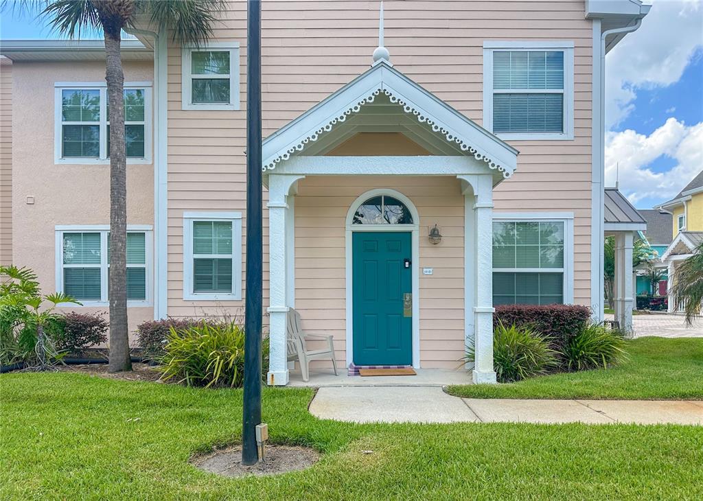 A two-story building with peach siding, a teal front door, and a covered entryway — 5006 MANGROVE ALLEY UNIT 101, KISSIMMEE, FL