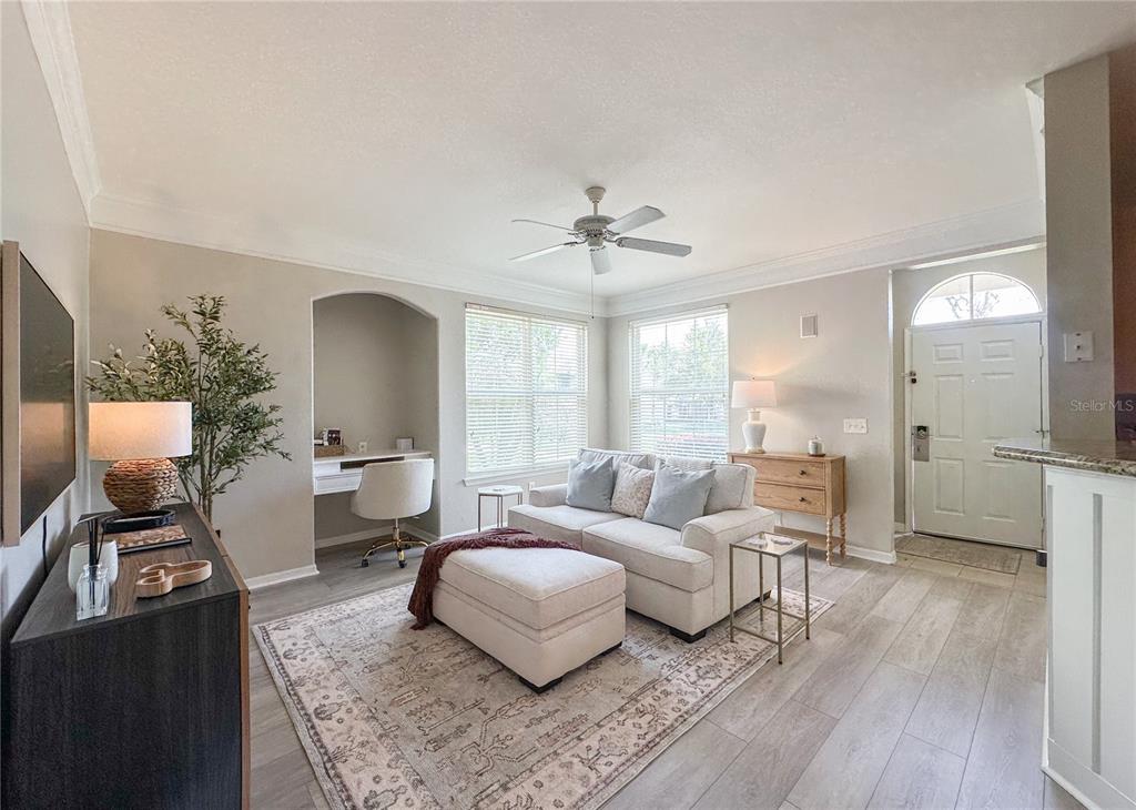 A living room features light wood flooring, a beige sofa with an ottoman, and a desk — 5006 MANGROVE ALLEY UNIT 101, KISSIMMEE, FL