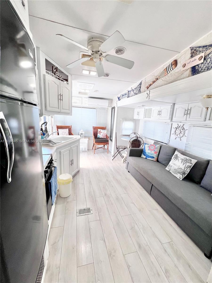 A narrow kitchen and living area in a mobile home with light wood flooring — 325 Calusa St # 5, Key Largo FL 33037, KEY LARGO, FL