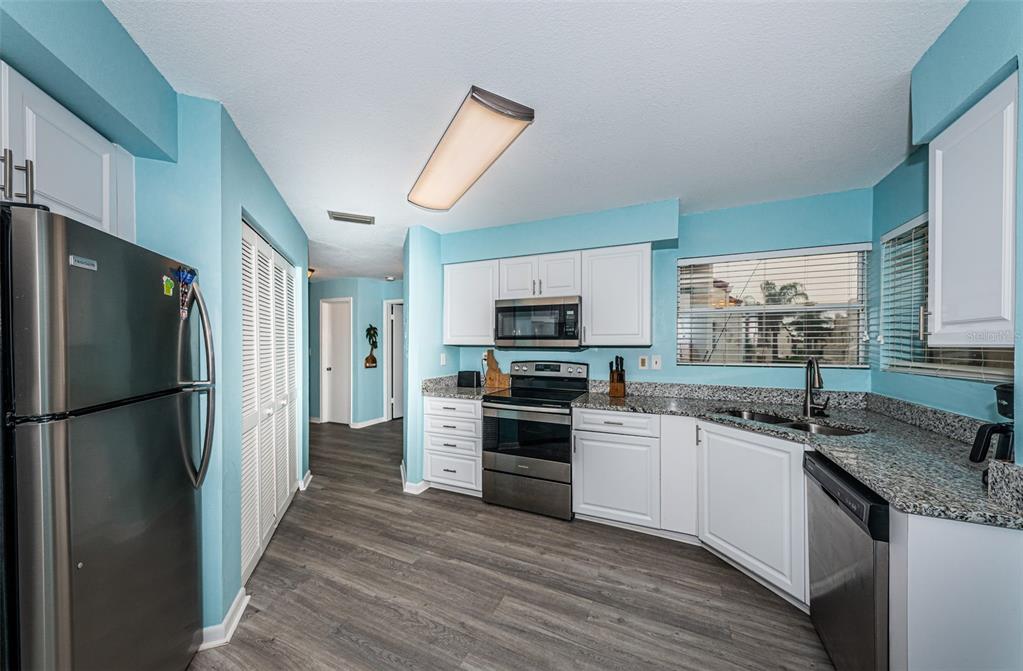 A kitchen with light blue walls, white cabinets, stainless steel appliances, and granite countertops — 6077 BAHIA DEL MAR BOULEVARD UNIT 224, ST PETERSBURG, FL