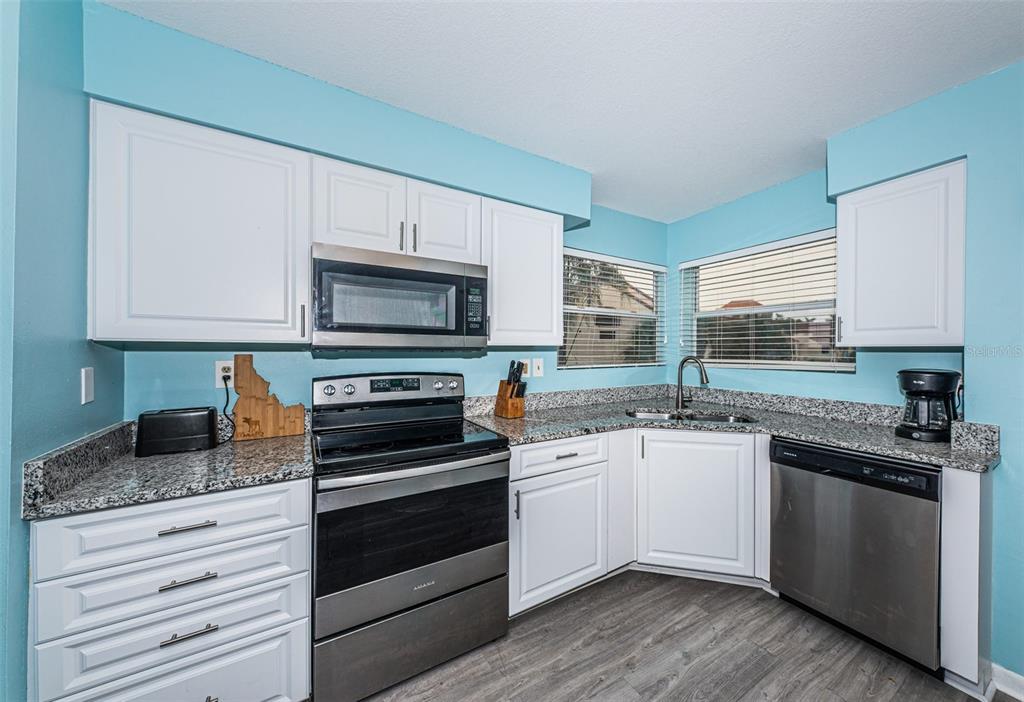 A kitchen with white cabinets, stainless steel appliances, granite countertops, and light blue walls — 6077 BAHIA DEL MAR BOULEVARD UNIT 224, ST PETERSBURG, FL
