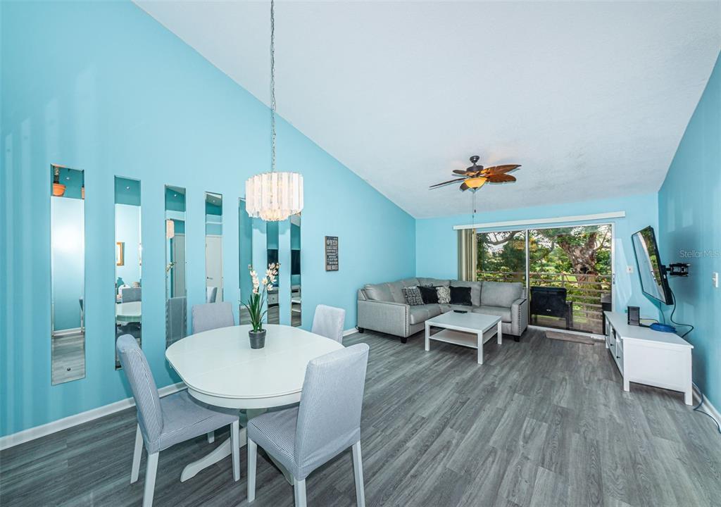 A dining and living area features light blue walls, gray wood flooring, and a sliding door — 6077 BAHIA DEL MAR BOULEVARD UNIT 224, ST PETERSBURG, FL