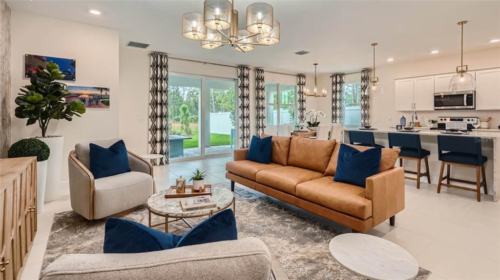 A modern open-concept living room features a leather sofa, armchairs, and a kitchen island — 7349 SW 45TH COURT, OCALA, FL
