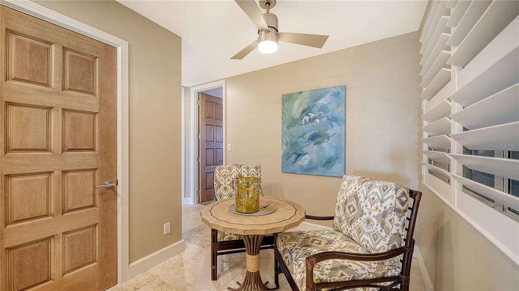 A small dining area features a round wooden table, two patterned chairs, and wall art — 2165 GULF OF MEXICO DRIVE UNIT 115, LONGBOAT KEY, FL