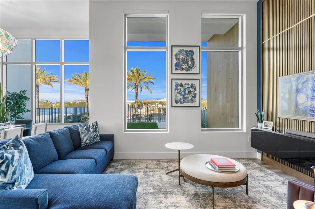 A living room features a blue sectional sofa, floor-to-ceiling windows, and a slatted wood wall — 5142 MARINA WAY, TAMPA, FL