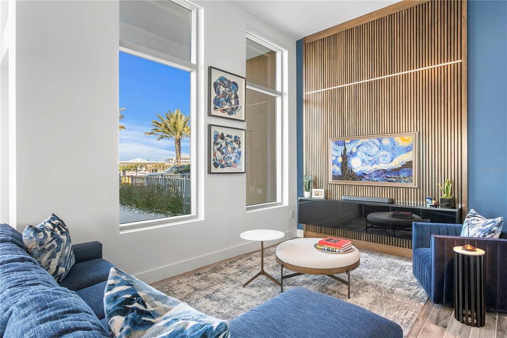 A living room features a slatted wood accent wall, blue furniture, and large floor-to-ceiling windows — 5142 MARINA WAY, TAMPA, FL