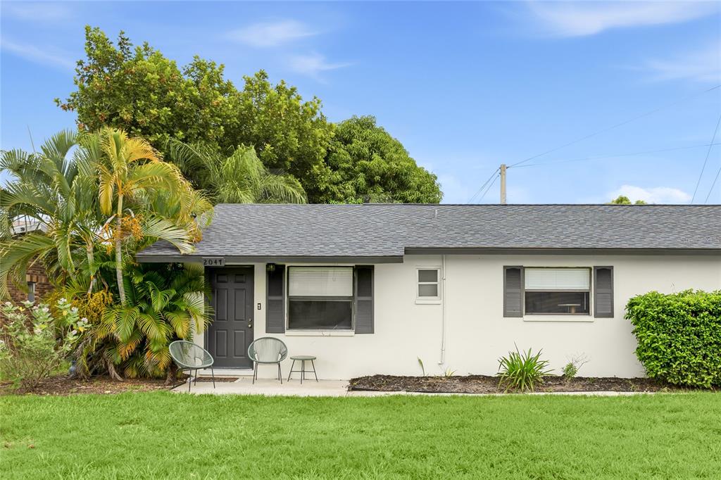 A single-story house exterior features a white facade, a dark front door, and a palm tree — 2047 & 2051 FIESTA DRIVE, SARASOTA, FL