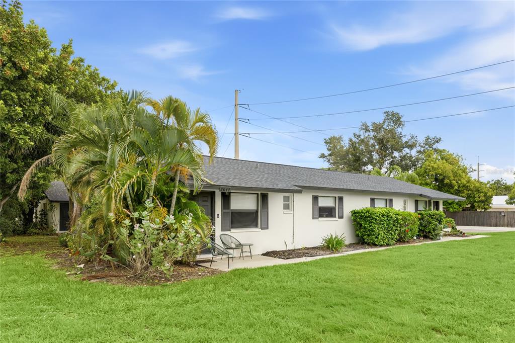 A single-story house with a white exterior, dark roof, and a palm tree in the yard — 2047 & 2051 FIESTA DRIVE, SARASOTA, FL