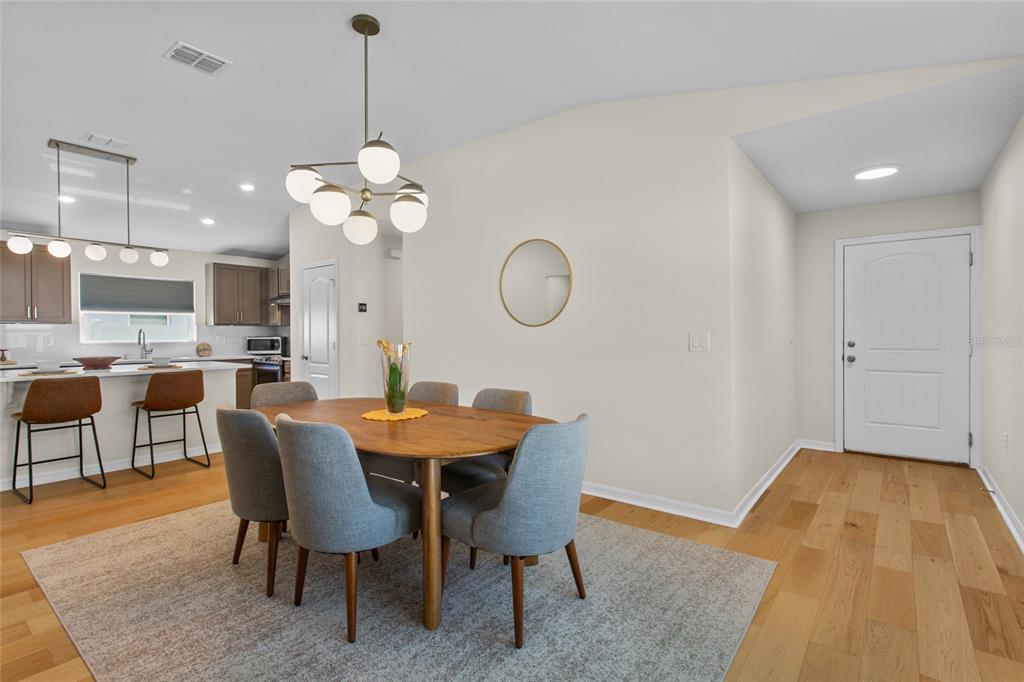 A dining area with a wooden table and grey chairs sits next to a kitchen — 4621 GLENCREST LOOP, ST CLOUD, FL